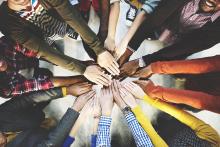 Image of people with hands extended together in a circle, representing teamwork.